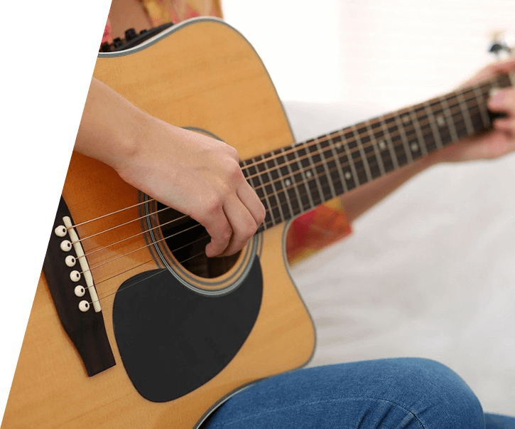 A person playing an acoustic guitar on the bed