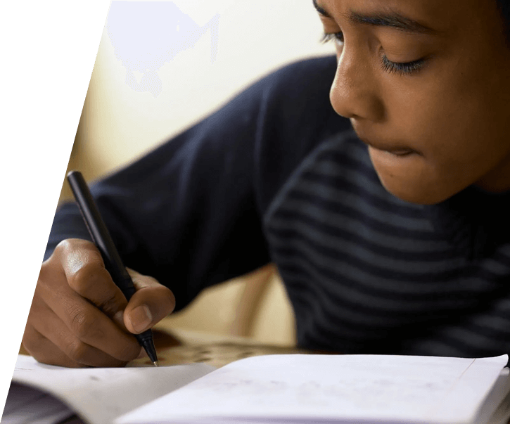 A boy is writing on paper with a pen.