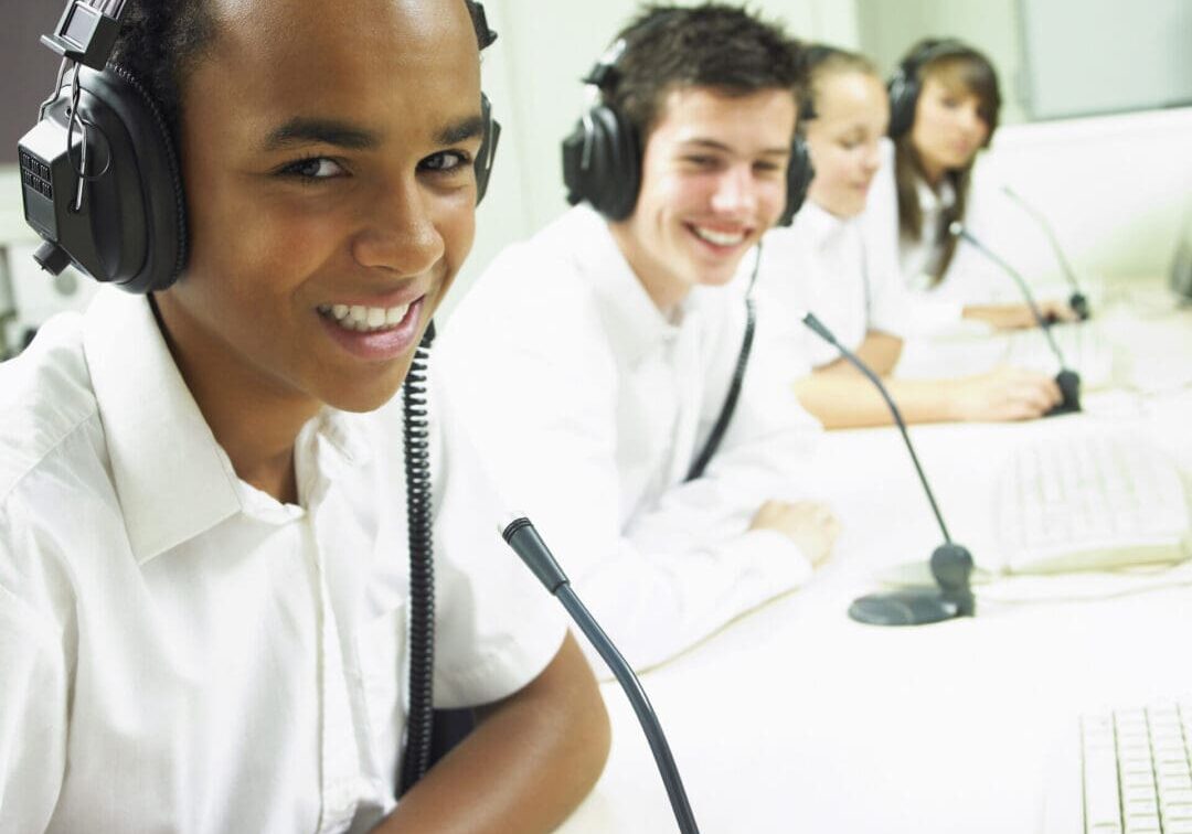 Students wearing headsets, smiling in a classroom setting.